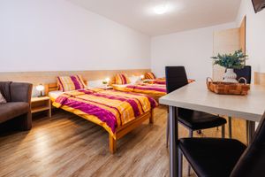 Třílůžkový pokoj s jídelním stolem a pohovkou