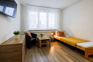 Jednolůžkový pokoj s hořčicovým přehozem, křeslem a stolkem u okna