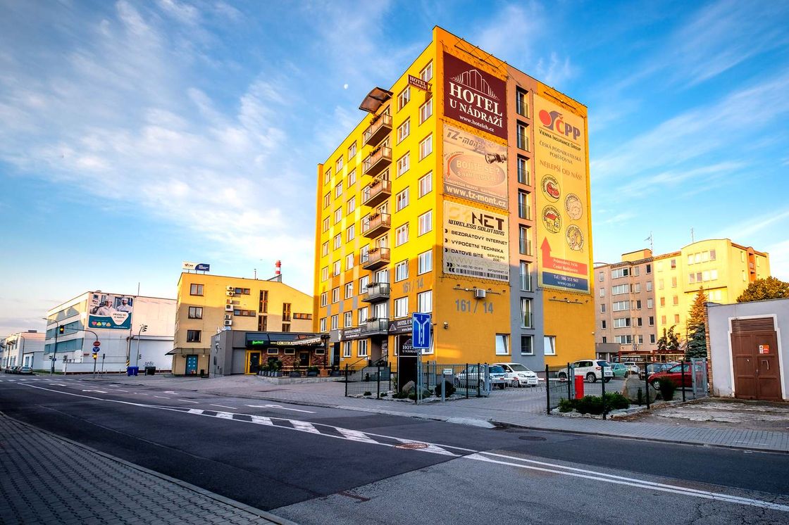 Žlutá budova Hotelu U Nádraží na rohu ulic Dvořákova a Novohradská v podvečerním světle