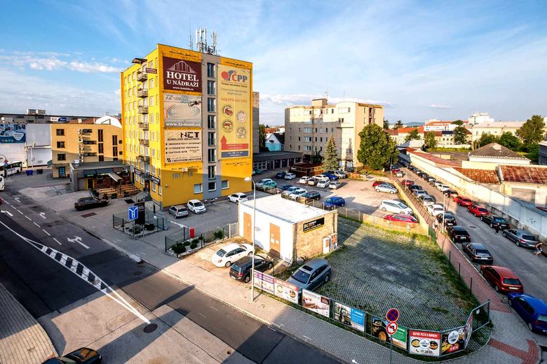 Pohled z výšky na budovu hotelu, okolní ulice a parkovací plochy